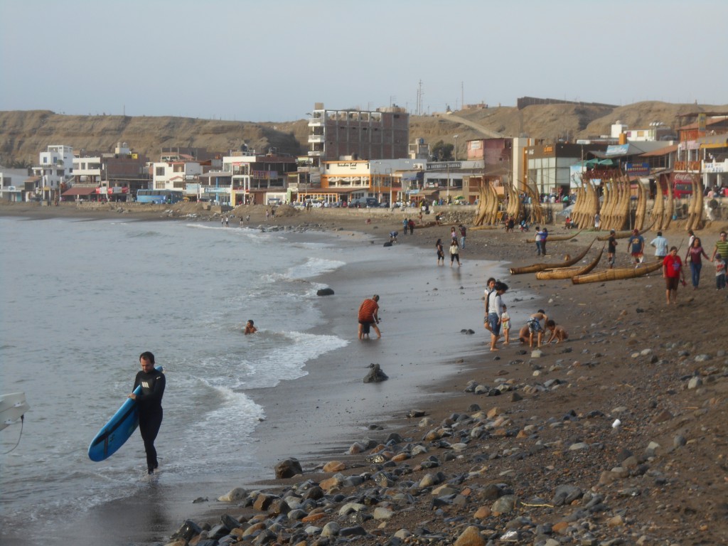 Huanchaco: Surfer und ortstypische Boote an der Strandpromenade